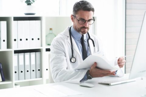 dr in front of computer reading documents